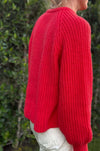 Red cardigan sweater with oversized sleeves and cozy knit texture worn outdoors