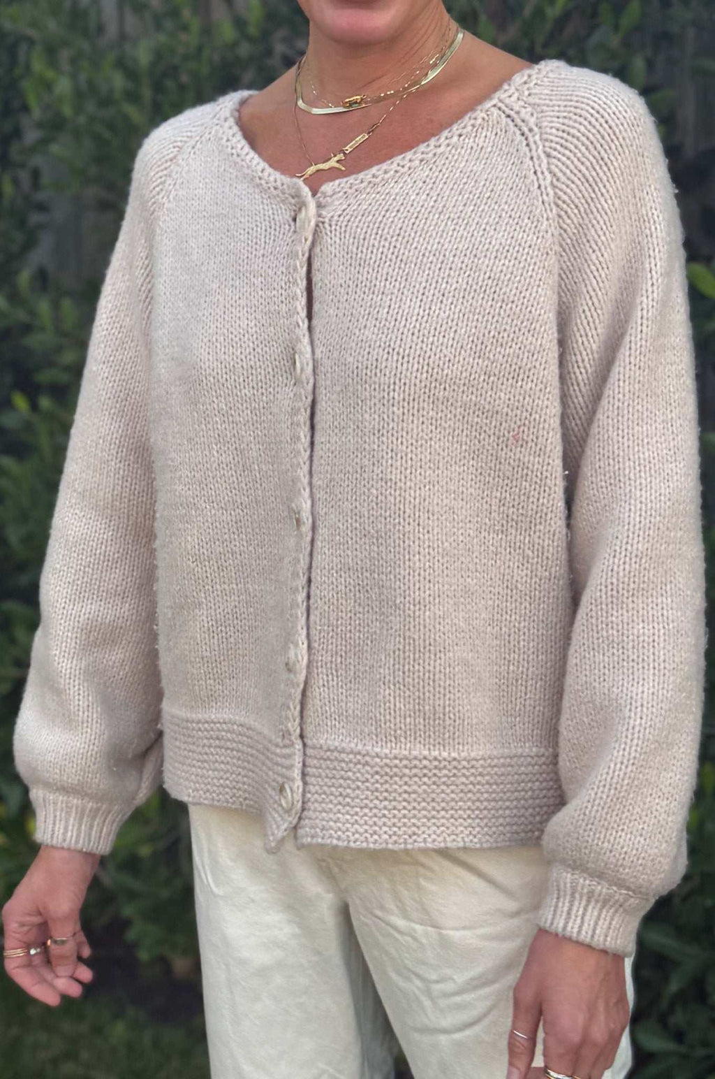 Woman wearing tan cardigan button down sweater with oversized sleeves and knit texture