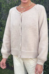 Woman wearing tan cardigan button down sweater with oversized sleeves and knit texture