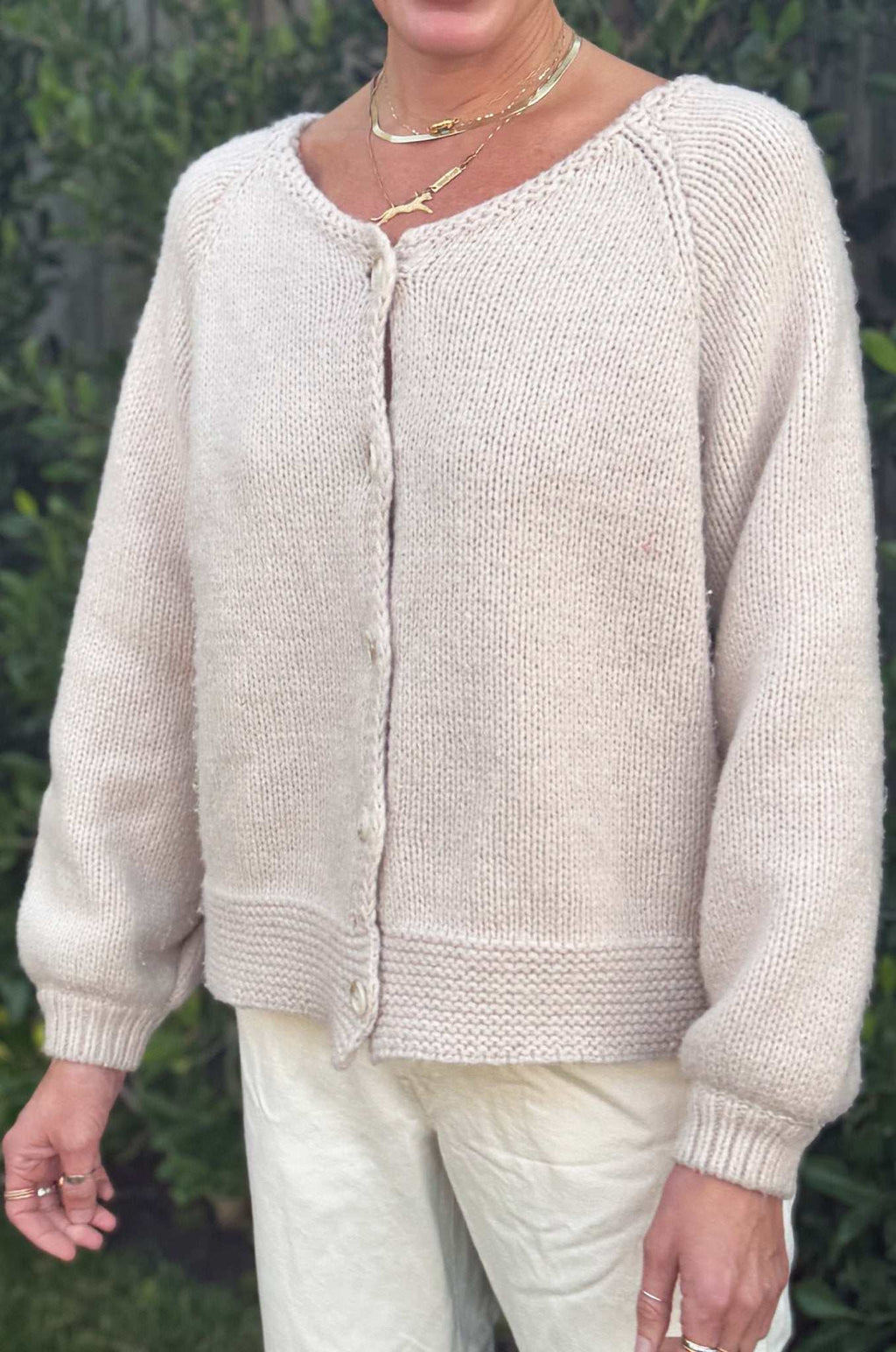 Woman wearing tan cardigan button down sweater with oversized sleeves and knit texture