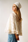 Ivory lace top with bohemian flair, high neck, ruffle trim, and flowy sleeves worn by model with headscarf
